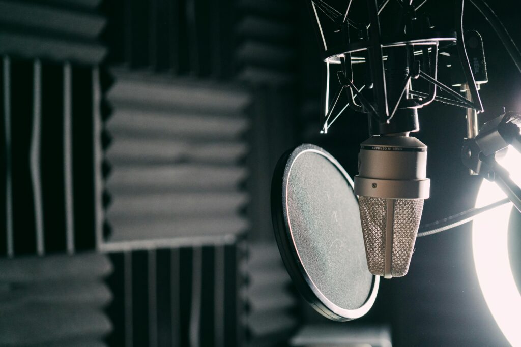 Close-up of a condenser microphone with pop filter in a professional sound studio.
